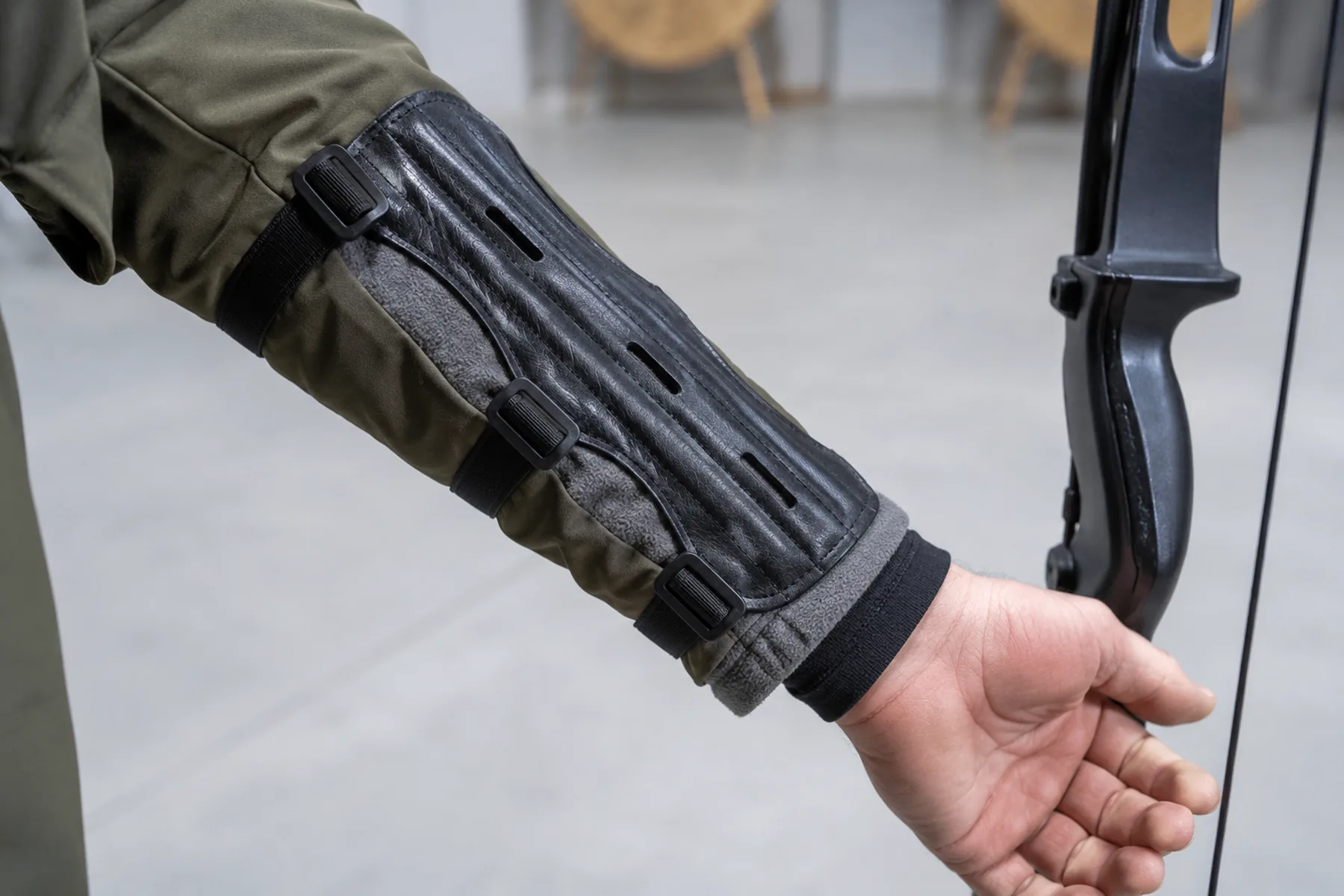 Bow arm wearing base layer, fleece and outer jacket with the arm guard compressing all three cuffs flat